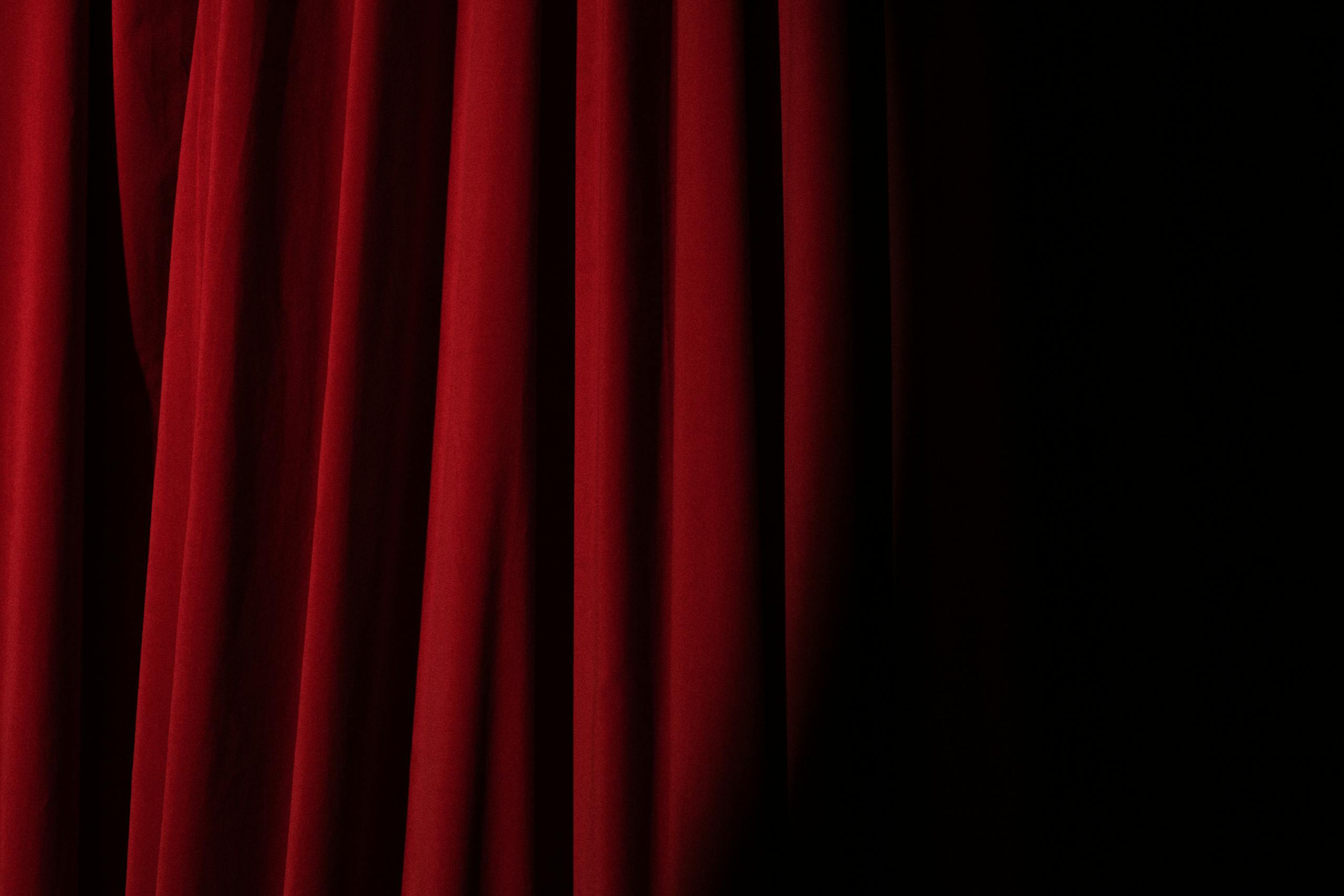Elegant red velvet curtain with dramatic lighting perfect for theater themes.