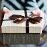 Stylish gift box with brown ribbon held in hands, perfect for holidays and celebrations.